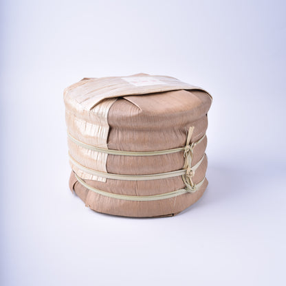 A tong of Ma Li Shu (Yibang) Gushu Spring 2022 Sheng / raw Puerh cake, bamboo wrapped.